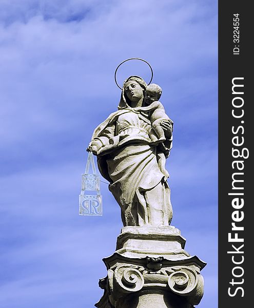 A statue of Our Lady with Child Jesus atop a lonely pillar in a square of the city of Bologna, Italy, as a symbol of protection of the people