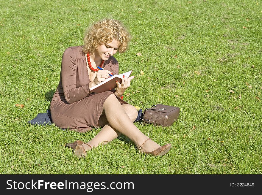 Business women with notebook sits on grass