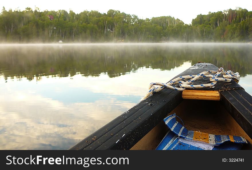 The bow of a canoe with the view of a peaceful lake in the background. The bow of a canoe with the view of a peaceful lake in the background.