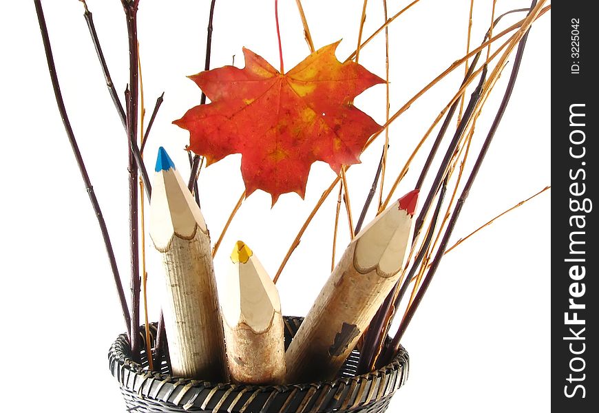 Autumn composition with leaf: coloured pencils in basket on white background