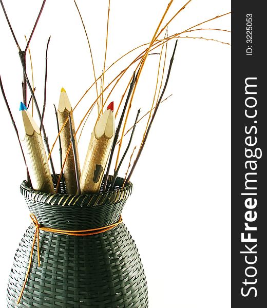 Composition of school and office articles: coloured pencils in basket on white background