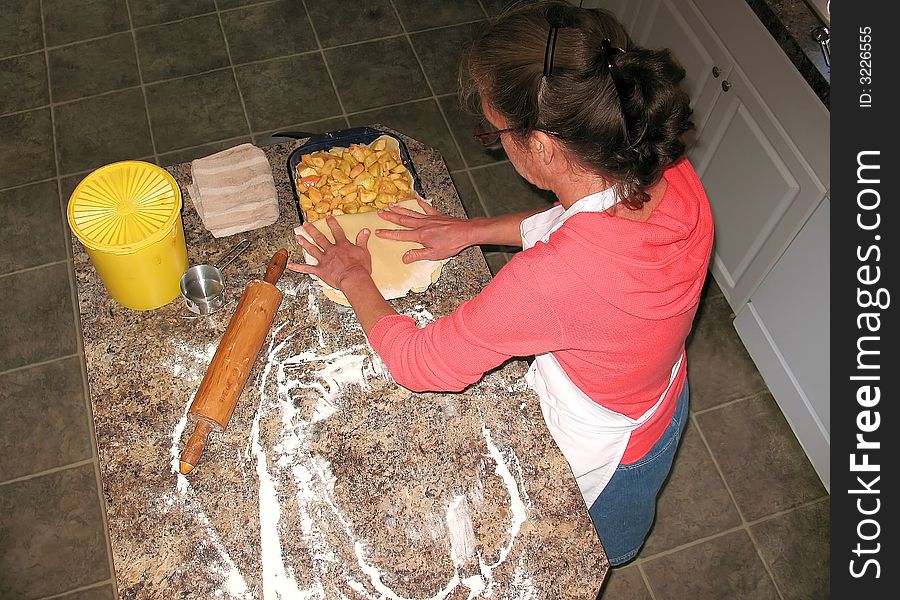 Woman making her own applepie, she made her own dough, and rolled it, placed it in the bowl, filled the bowl with apples and sugar, and then we see her with another piece of rolled dough that she is covering the pie with. Woman making her own applepie, she made her own dough, and rolled it, placed it in the bowl, filled the bowl with apples and sugar, and then we see her with another piece of rolled dough that she is covering the pie with.