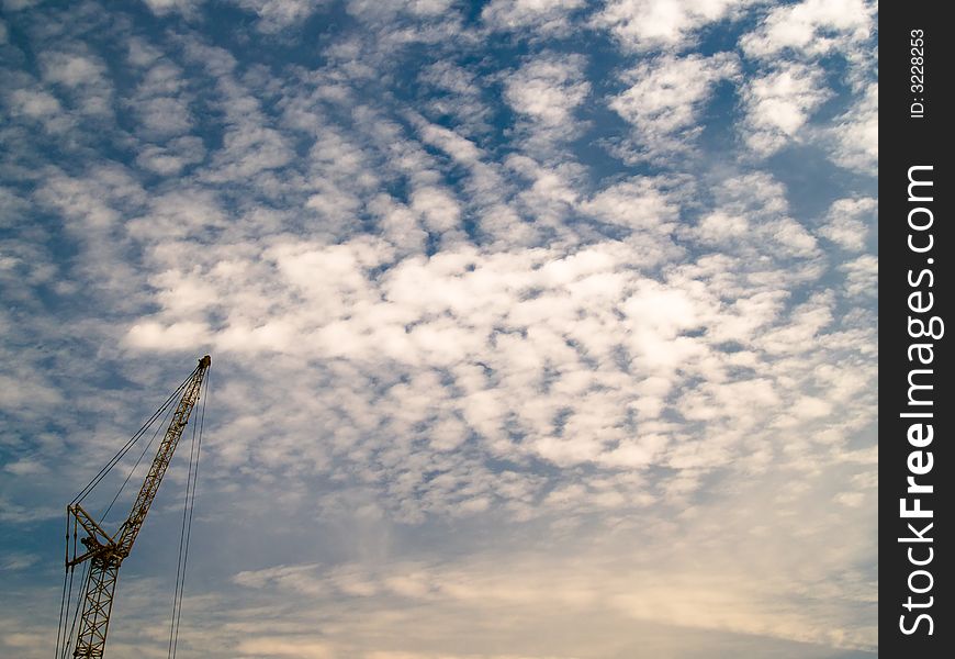 A tall crane silhouetted against a altocumulus mackerel sky. A tall crane silhouetted against a altocumulus mackerel sky.