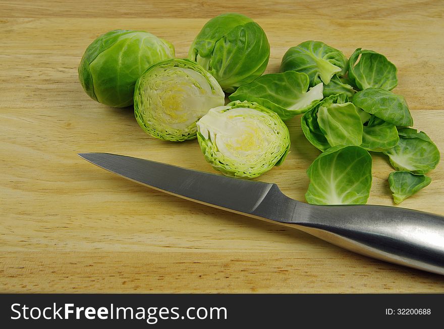 Brussel sprouts cut and peeled with silver knife on wooden background. Brussel sprouts cut and peeled with silver knife on wooden background