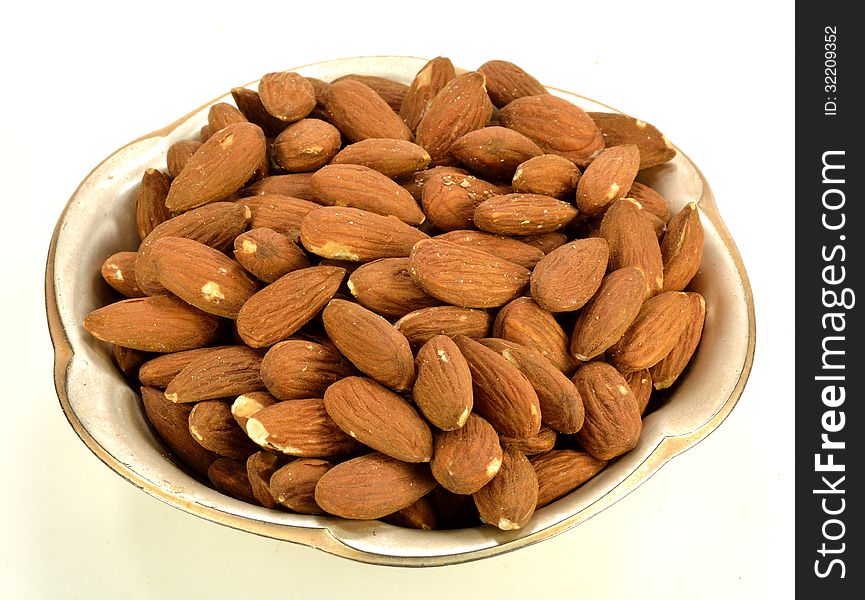 A small metal dish of shelled almonds.