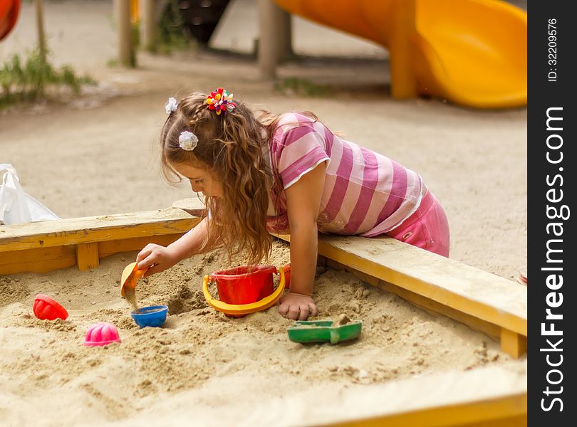 Little girl playing in the sandbox. Little girl playing in the sandbox