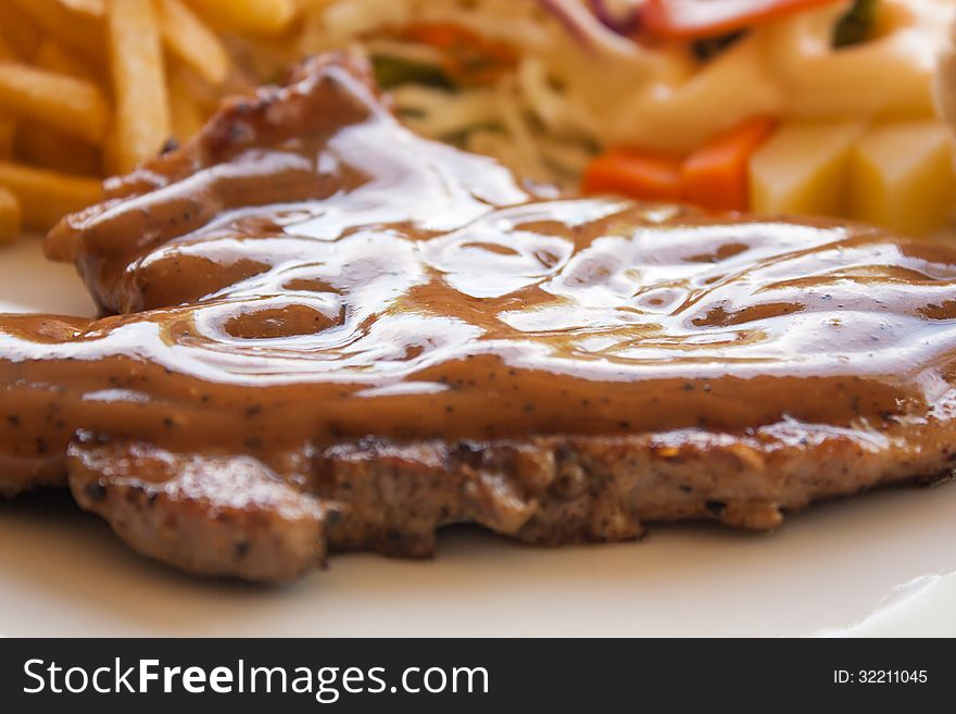 Pork chop steak with black pepper gravy salad and french fries