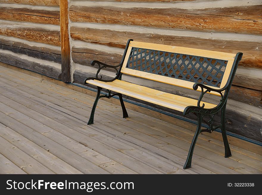 Empty Bench in front of Log Cabin setting on wooden walkway. Empty Bench in front of Log Cabin setting on wooden walkway.