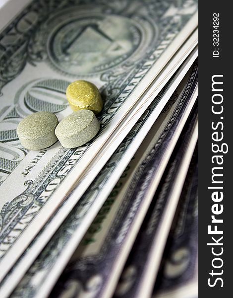 Pills of different colors on money background. Pills of different colors on money background.