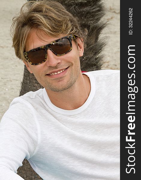 Young male wearing sunglasses on vacation at the beach. Young male wearing sunglasses on vacation at the beach
