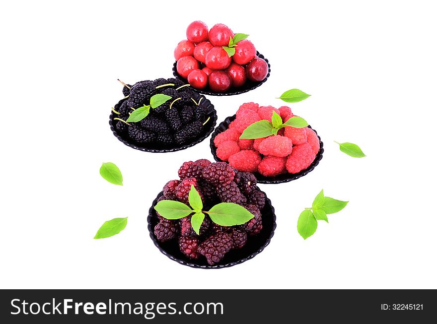 Mulberry; cherry; raspberry; blackberry in a plates close-up isolated on white; decorated with green leaves. Mulberry; cherry; raspberry; blackberry in a plates close-up isolated on white; decorated with green leaves.