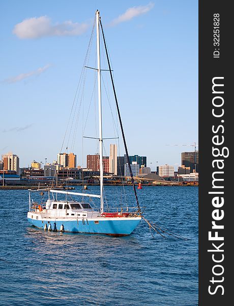 A yacht lying at anchor in Durban harbour, KwaZulu-Natal, South Africa, with the city skyline in the background. A yacht lying at anchor in Durban harbour, KwaZulu-Natal, South Africa, with the city skyline in the background