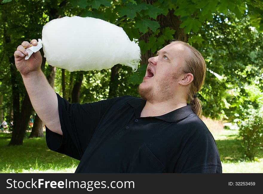 Man with cotton candy in a city park