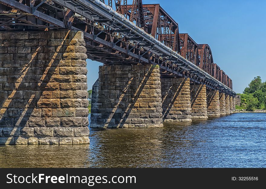 Stone and steel train bridge passing over a river