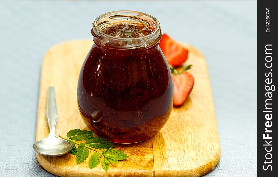 Strawberry jam and fresh fruits on wooden cutting board