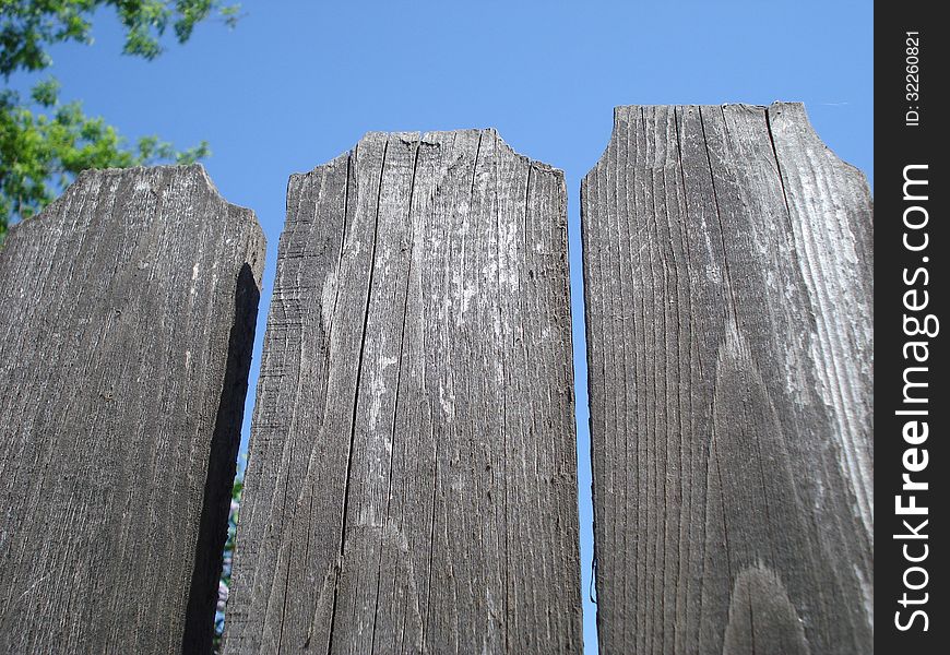 Top of old wooden fence on blue sky. Top of old wooden fence on blue sky