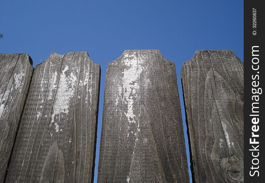 Top of old wooden fence on blue sky. Top of old wooden fence on blue sky