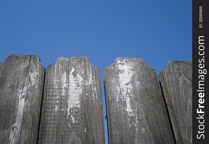 Top of old wooden fence on blue sky. Top of old wooden fence on blue sky