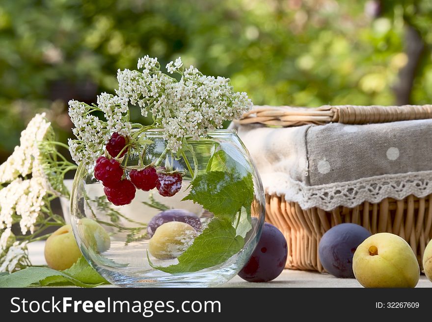 Ripe fruit and wild flowers in a glass bowl and basket