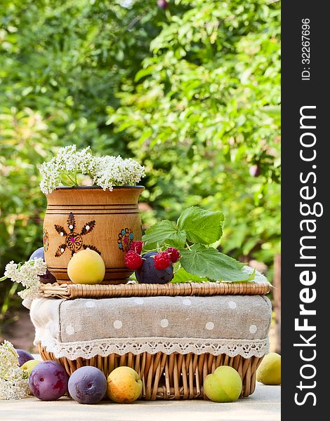 Ripe fruits, wild flowers, a basket and a wooden bowl on the table in the garden. Ripe fruits, wild flowers, a basket and a wooden bowl on the table in the garden