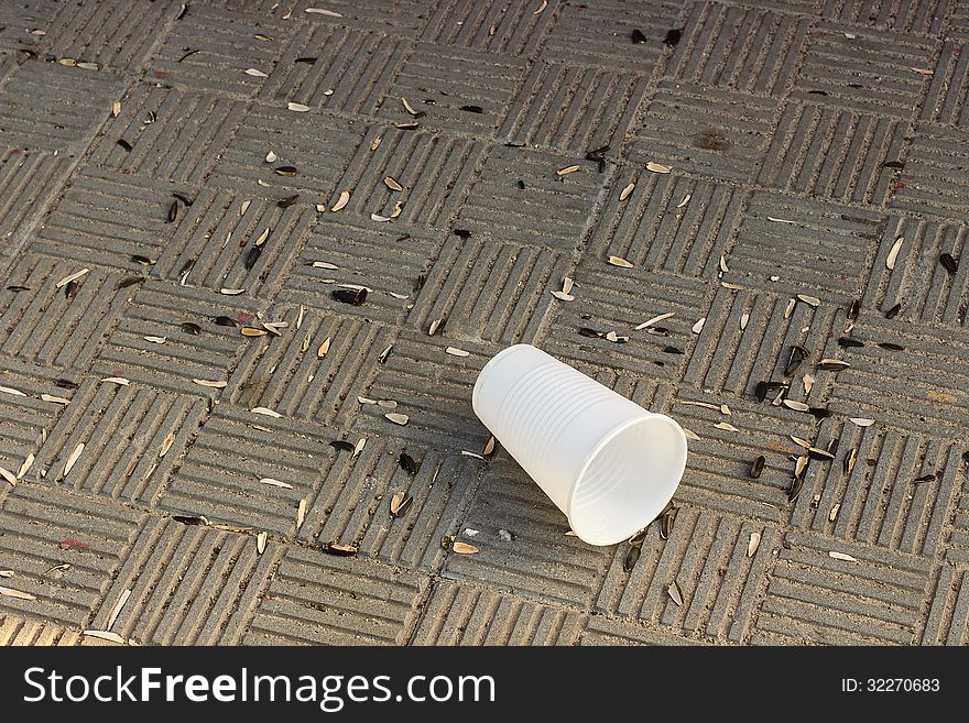 Husks sunflower seeds and a cup on a stone tile