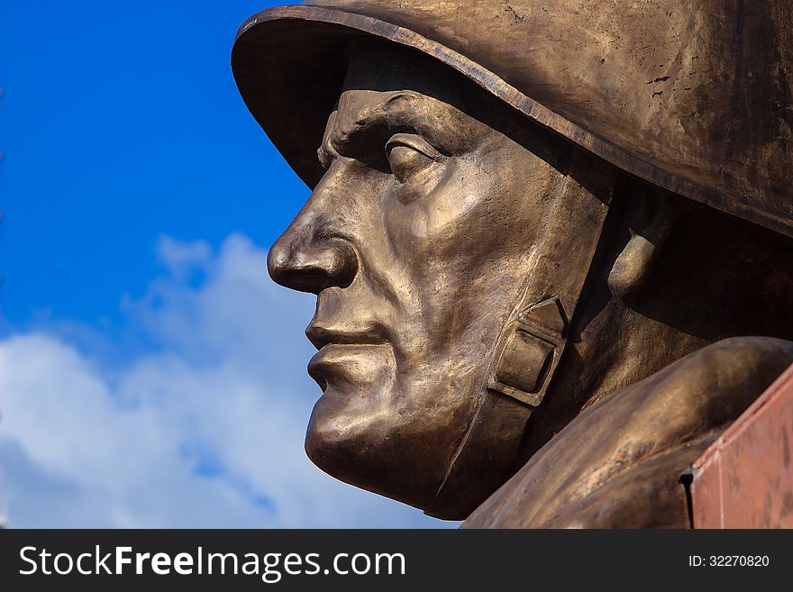 Face of a russian soldier made ​​of bronze against blue sky. Face of a russian soldier made ​​of bronze against blue sky