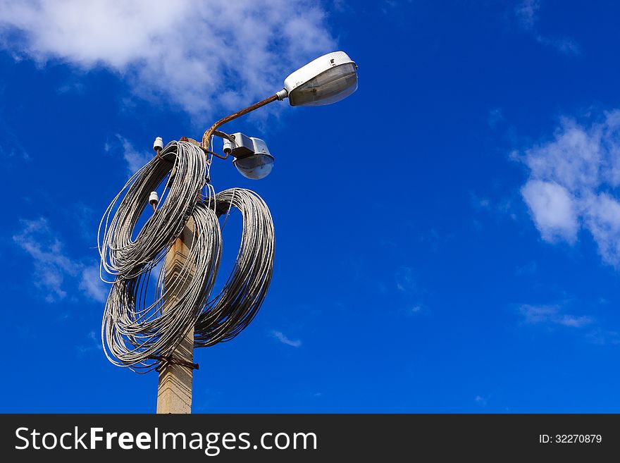 A coils of metal wire hangigns on a lamppost over blue sky. A coils of metal wire hangigns on a lamppost over blue sky