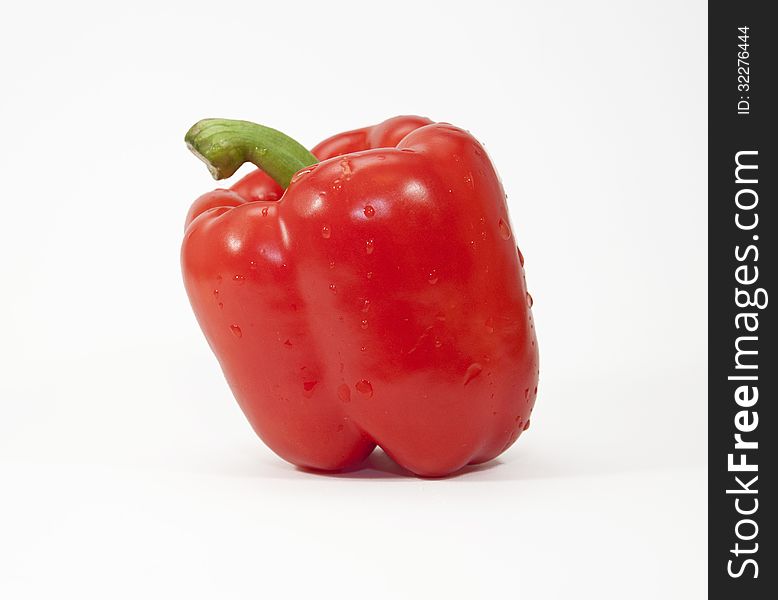 Red pepper with water droplets against a white background