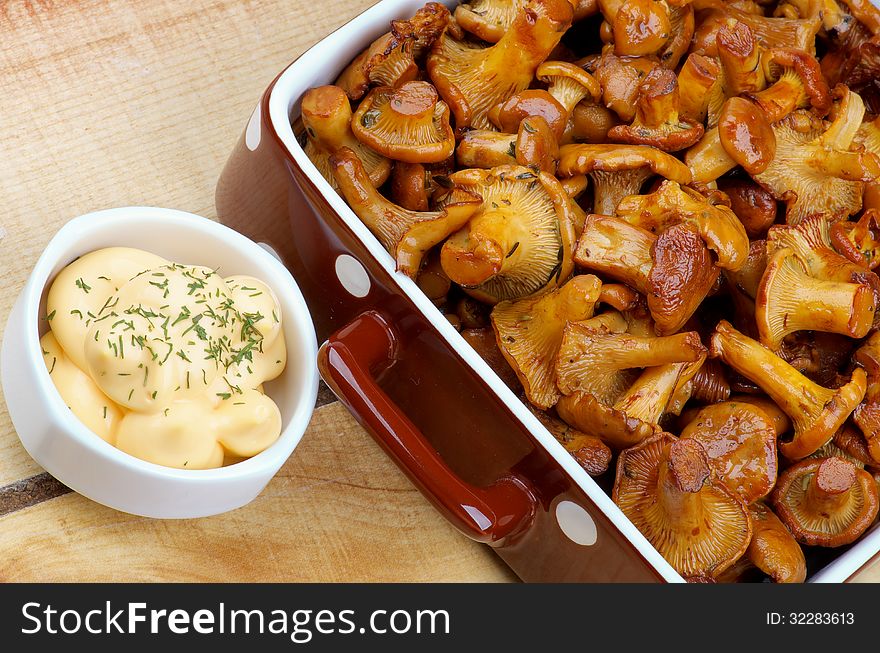 Delicious Roasted Chanterelles in Brown Polka Dot Bowl with Cream Cheese Sauce on Wooden background