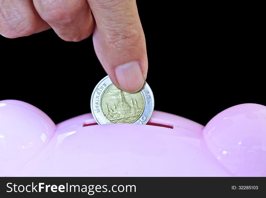 Hand inserting coin into piggy bank. Hand inserting coin into piggy bank