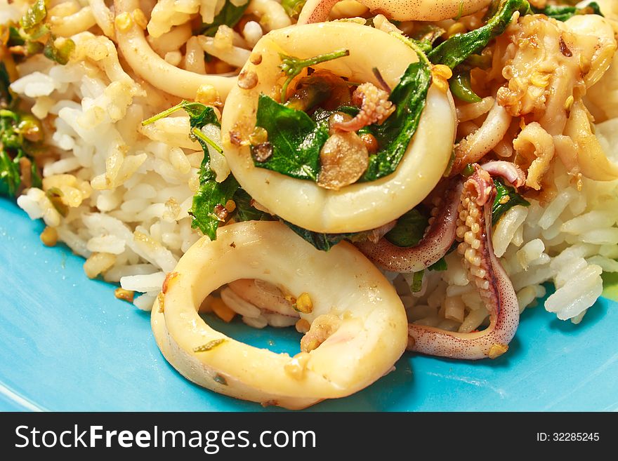 Squids fried with chilli pepper and sweet basil on rice