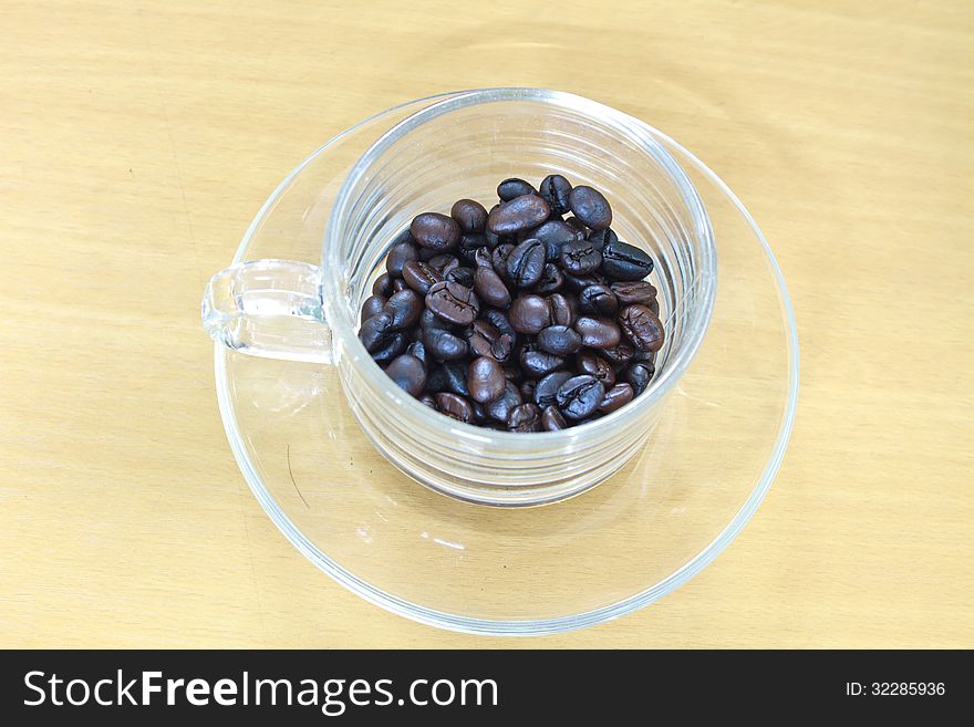 Coffee beans in cup on the wood table