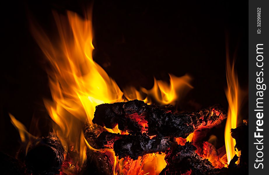 Live coals with fire flames on black background