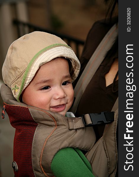 Image of a biracial baby riding in a front carrier on his mom