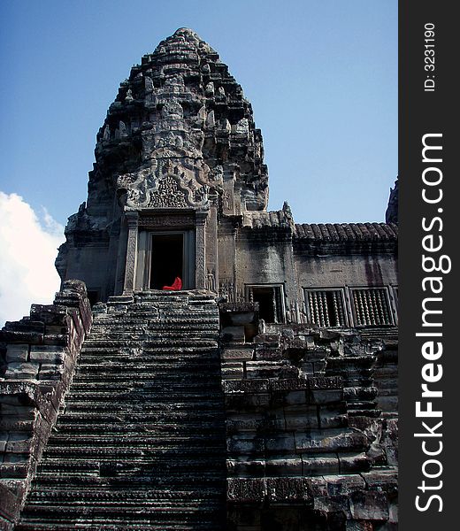 Monk sitting in doorway at top of temple stairway. Monk sitting in doorway at top of temple stairway