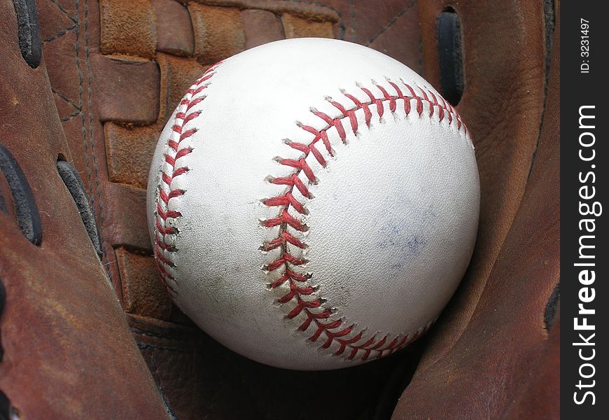 A baseball caught in the glove. A baseball caught in the glove