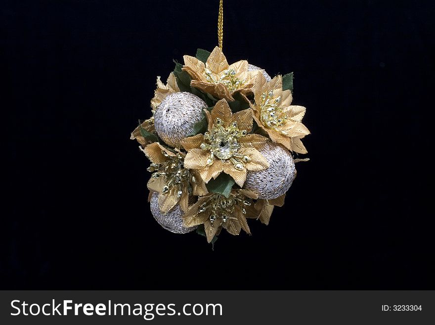 A gold and silver christmas decoration photographed against a black background