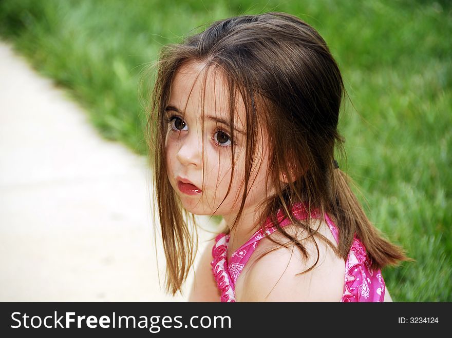 A beautiful little girl sitting on the window sill.  She's dressed in turquoise and has a matching bow in her long brown hair. A beautiful little girl sitting on the window sill.  She's dressed in turquoise and has a matching bow in her long brown hair.