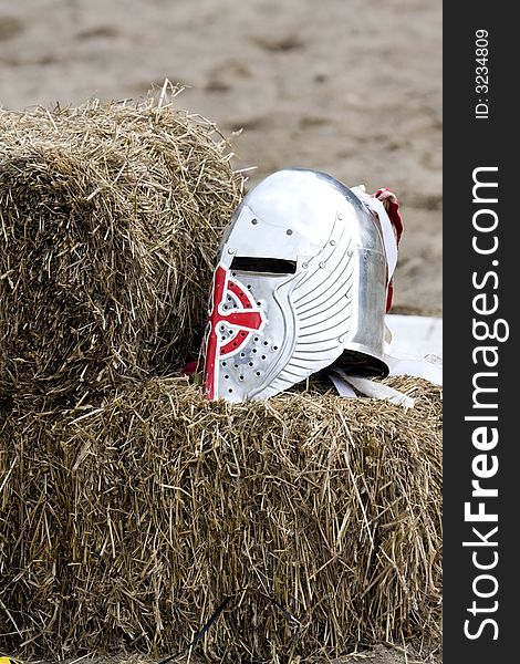 A knight's helmet lays on a bale of straw. A knight's helmet lays on a bale of straw.