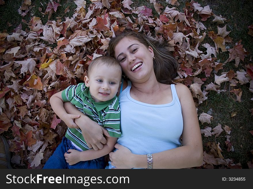 Son and Mother being affectionate on a pile of leaves. Son and Mother being affectionate on a pile of leaves