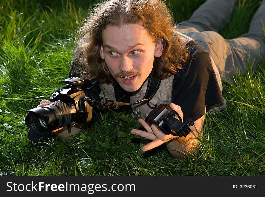 The photographer with the camera lays on a green grass