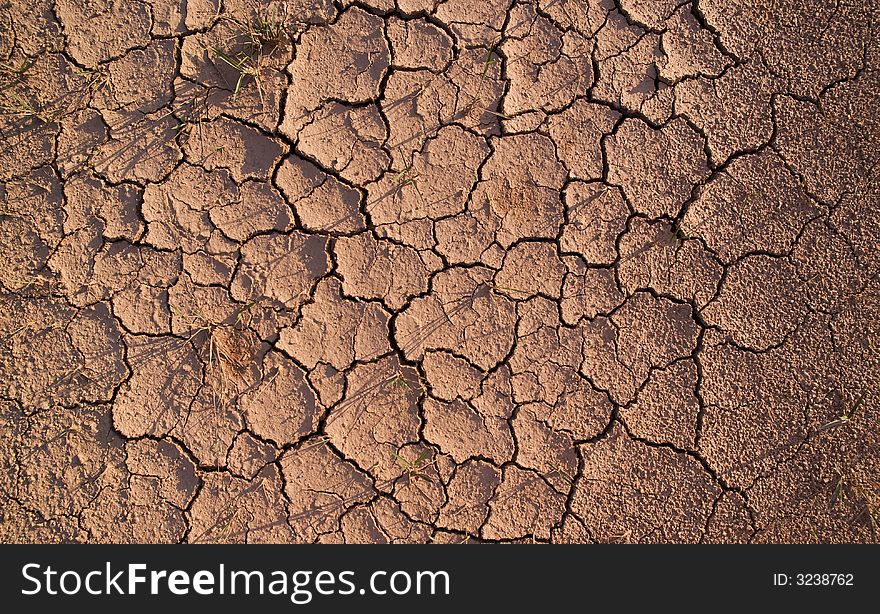 Dirt track with dry mud, cracked with gaps and holes