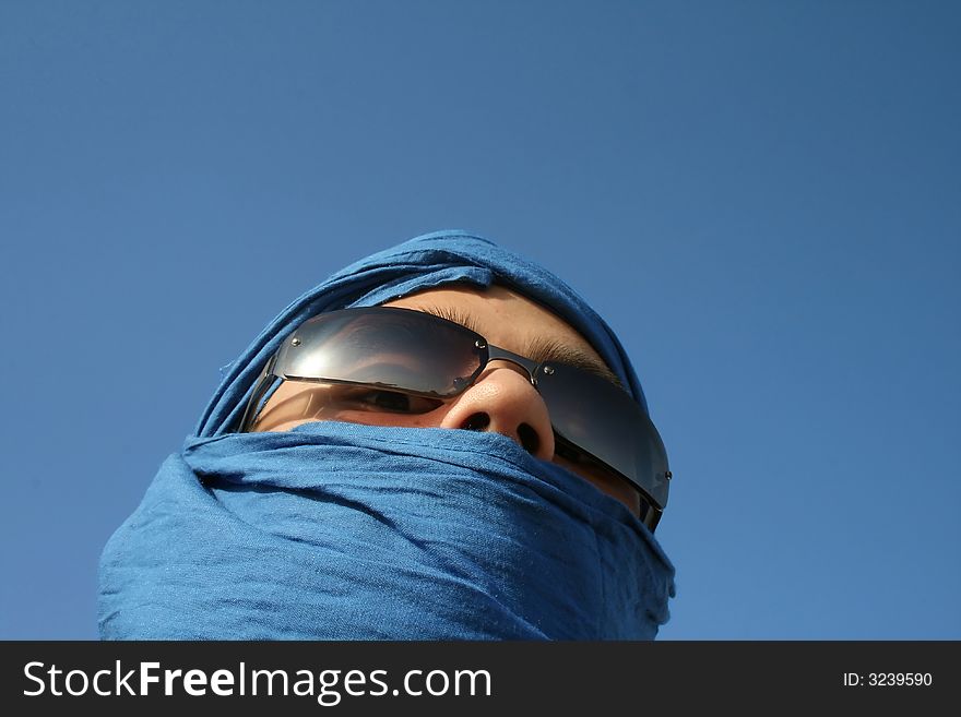Face of a man in sahar desert covered with blue fabric