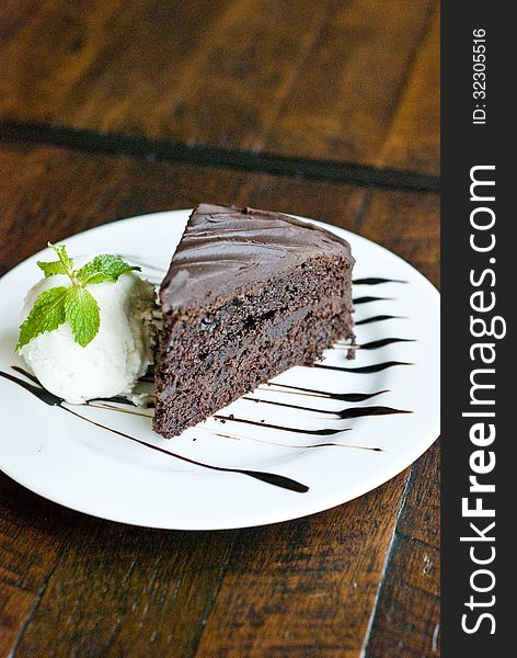 Portion of chocolate cake with vanila ice-creme on white plate topping with chocolate sauce