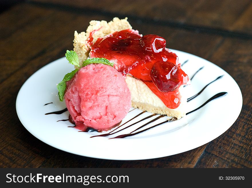 Horizon view of portion of strawberry cheese cake and strawberry ice-creme on white plate topping with chocolate sauce