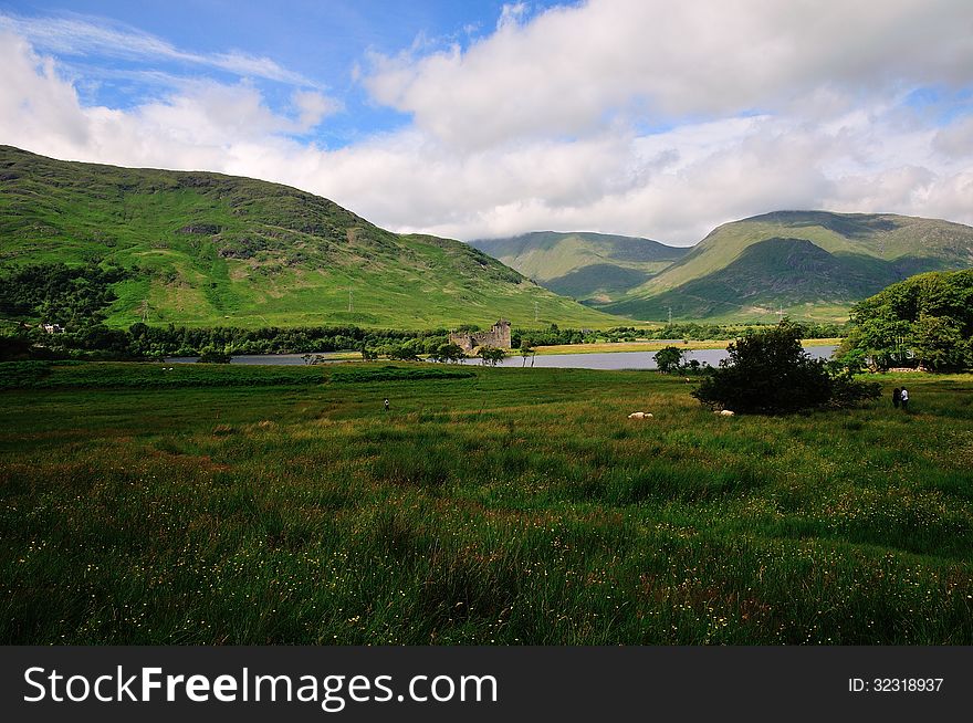 A Ruined Scottish Castle, Overlooked By Mountains.