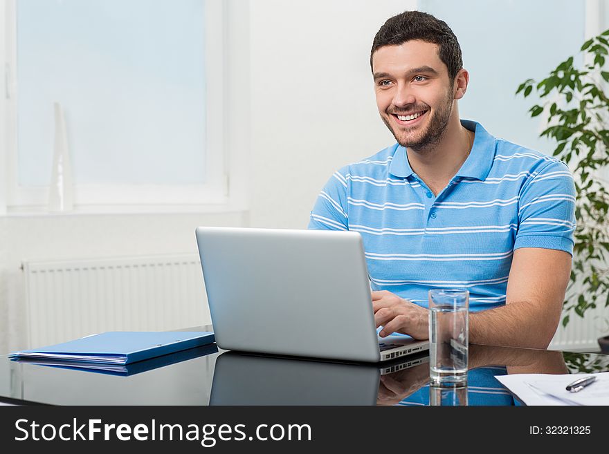 Happy young businesswoman sitting at table with laptop