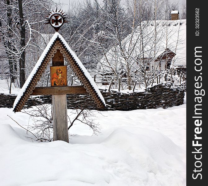 Orthodox Icon of the Mother of God with Child on a carved wooden cross on the outskirts of the village under the snow. Orthodox Icon of the Mother of God with Child on a carved wooden cross on the outskirts of the village under the snow