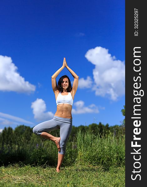 Girl doing yoga outdoor with open eyes and smiling, vertical. Girl doing yoga outdoor with open eyes and smiling, vertical