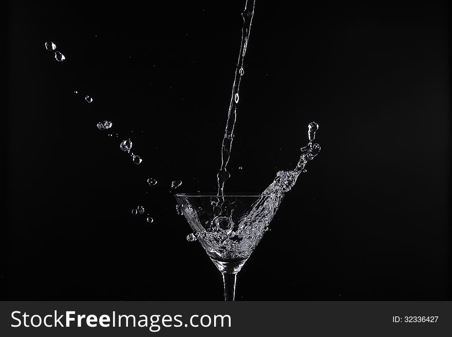 Pouring water into glass with black background. Pouring water into glass with black background